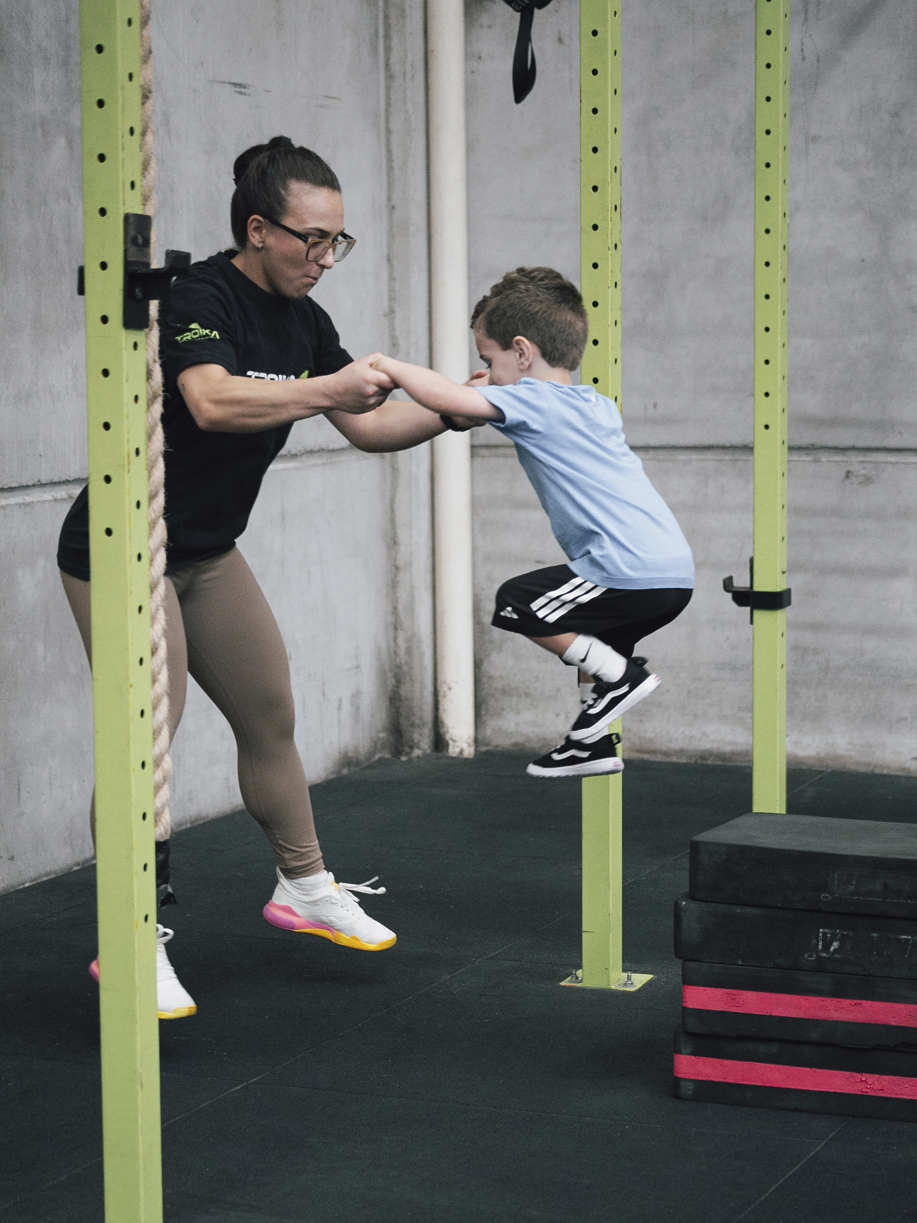 Criança praticando um salto com acompanhamento da coach no Cross Kids